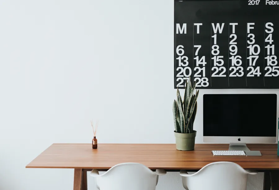 Escritorio ordenado frente a un calendario mensual de pared